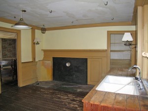 Room 106, new kitchen. This room retains its period cooking hearth and bake oven. The wrought iron hooks in the ceiling are original to the space.
